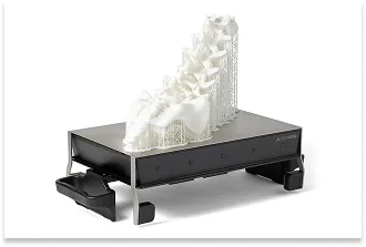 A white prototype with highly complex, organic geometry, printed from SLA resin on a working platform with support structures.