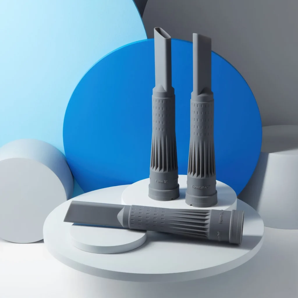 Three grey technical components with complex geometry, precisely printed using 3D SLA resin technology.