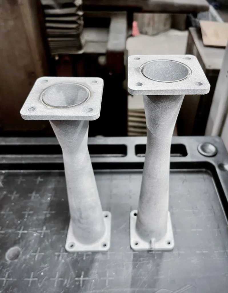 Two polymer intake restrictors for a racing car, 3D printed, showing precise mounting flanges and smooth internal transitions.